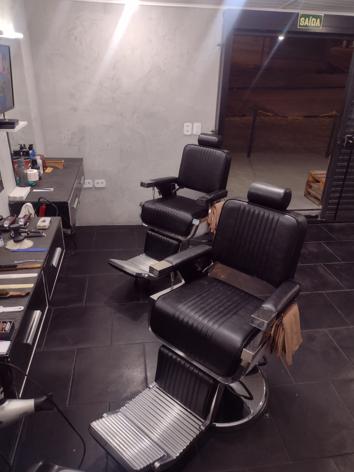 Cadeiras de atendimento vazias dentro da Barbearia Thom