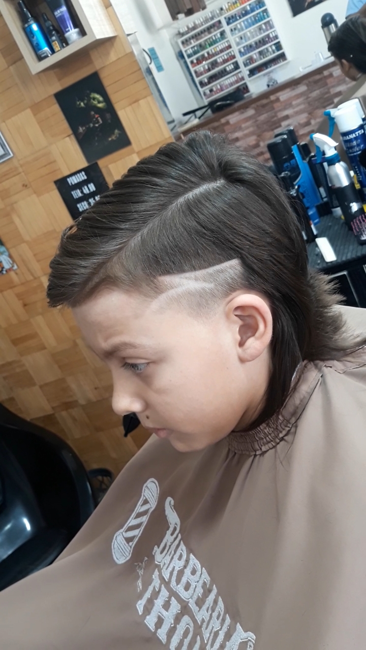 Criança sendo atendida na Barbearia Thom, com a capa de corte estampada